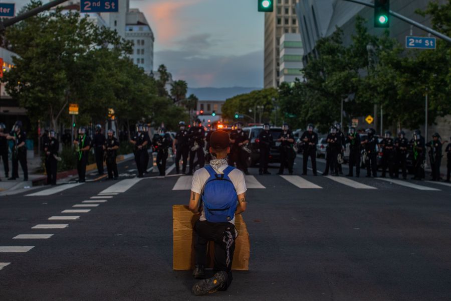 A demonstrator kneels in front of a Police line in Downtown Los Angeles on May 30, 2020, during a protest against the death of George Floyd, an unarmed black man who died while while being arrested and pinned to the ground by the knee of a Minneapolis police officer. (APU GOMES/AFP via Getty Images)