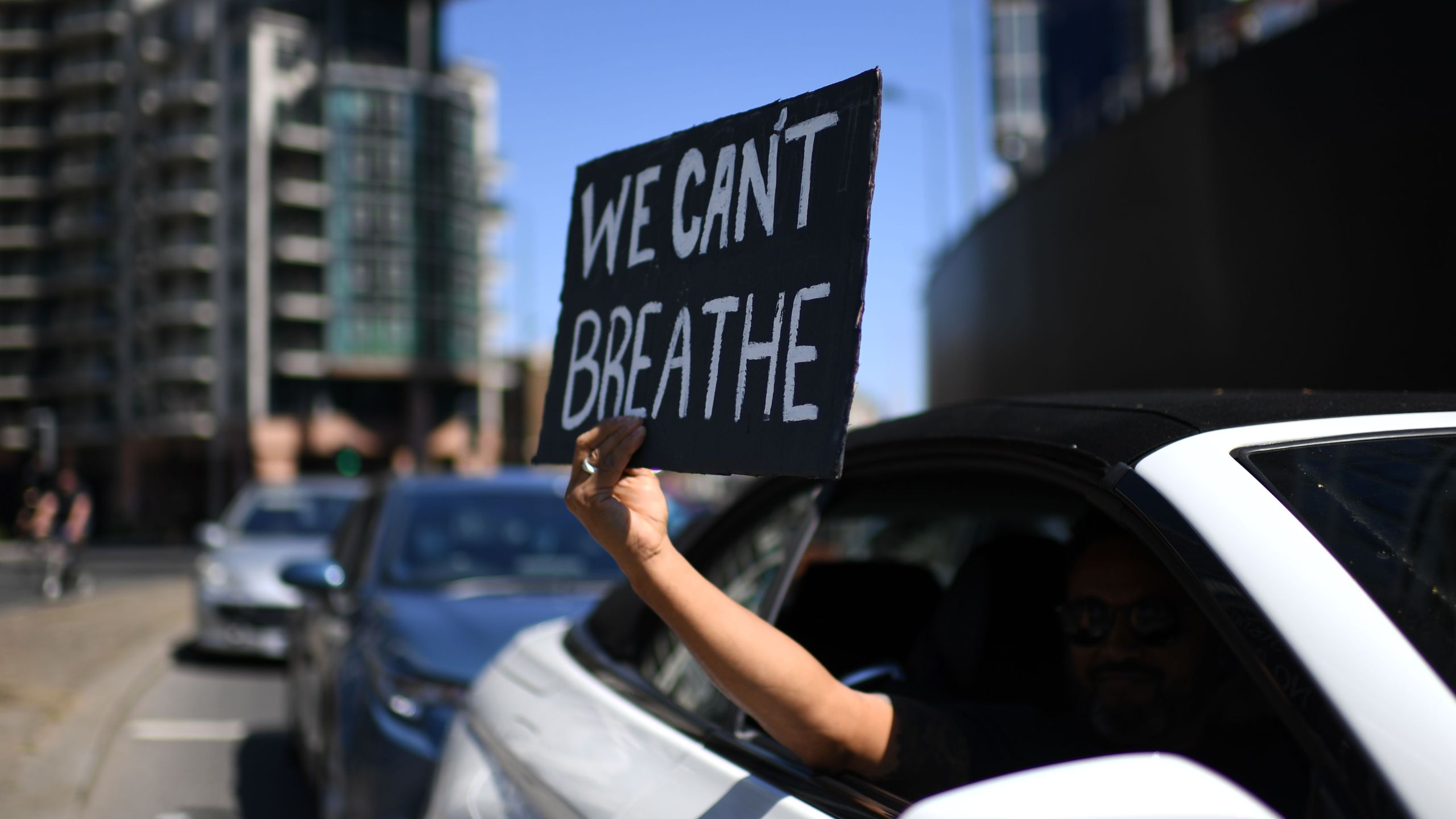 A sign displaying the message "We Can't Breathe" is held out of a car window as demonstrators make their way towards the U.S. Embassy in central London on May 31, 2020, to protest the death of George Floyd, who died after a police officer knelt on his neck for nearly nine minutes during an arrest in Minneapolis. (DANIEL LEAL-OLIVAS/AFP via Getty Images)