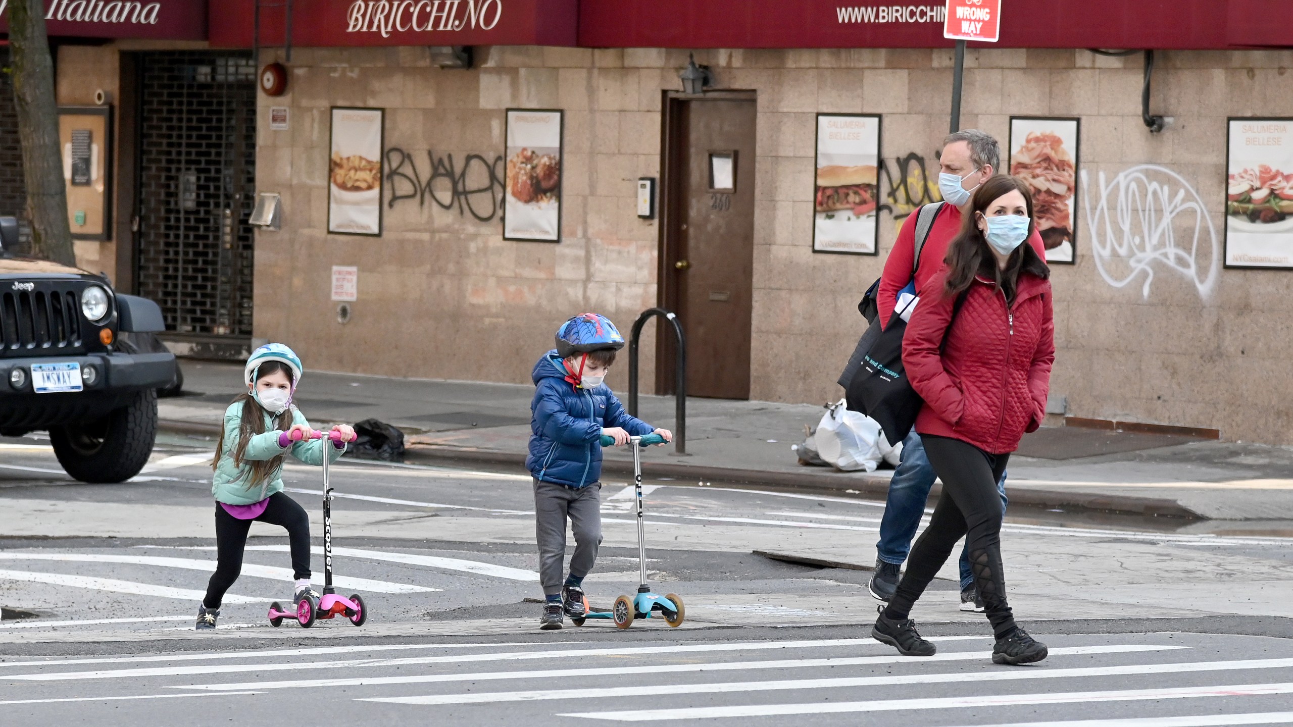 Children wearing face masks play on their scooters while their parents watch during the coronavirus pandemic on April 25, 2020 in New York City. (Jamie McCarthy/Getty Images)