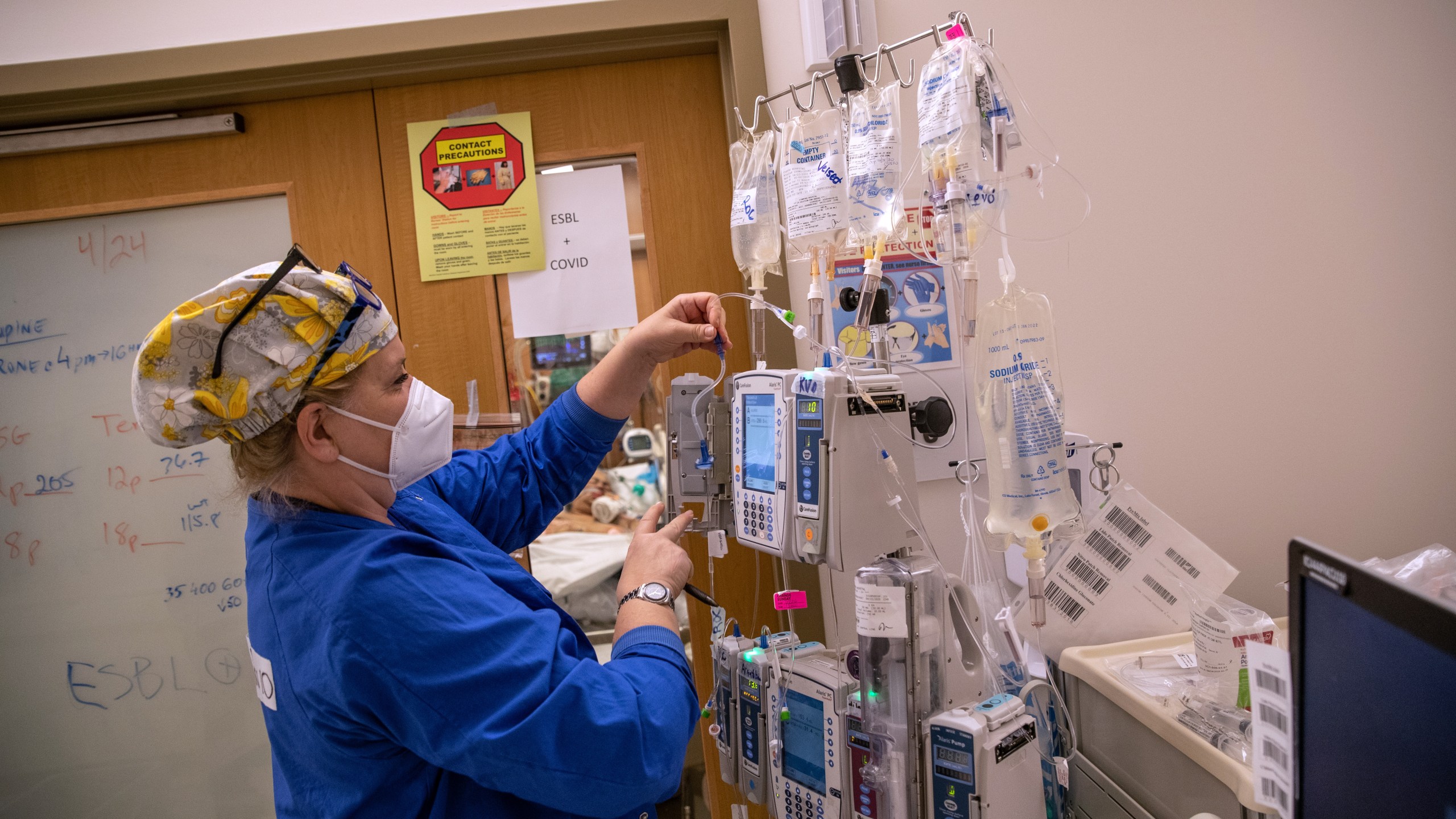 A nurse wearing an N95 mask adjusts IV equipment hanging outside a COVID-19 patient's door in a Stamford Hospital intensive care unit (ICU), on April 24, 2020, in Stamford, Conn. (John Moore/Getty Images)