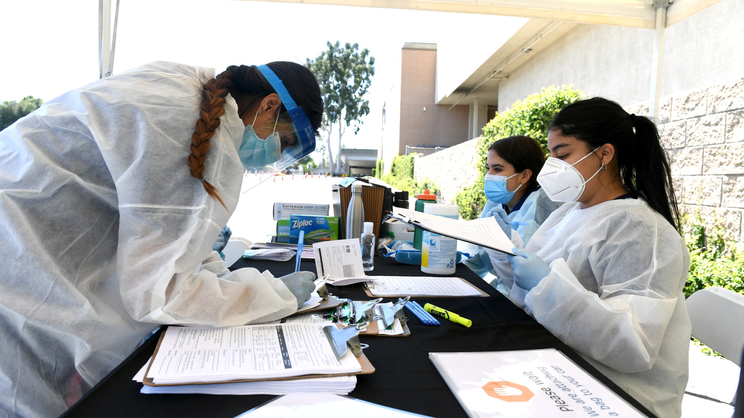 Workers wearing personal protective equipment (PPE) perform drive-up COVID-19 testing administered from a car at Mend Urgent Care testing site for the novel coronavirus at the Westfield Fashion Square on May 13, 2020, in the Sherman Oaks neighborhood of Los Angeles. (Kevin Winter/ Getty Images)