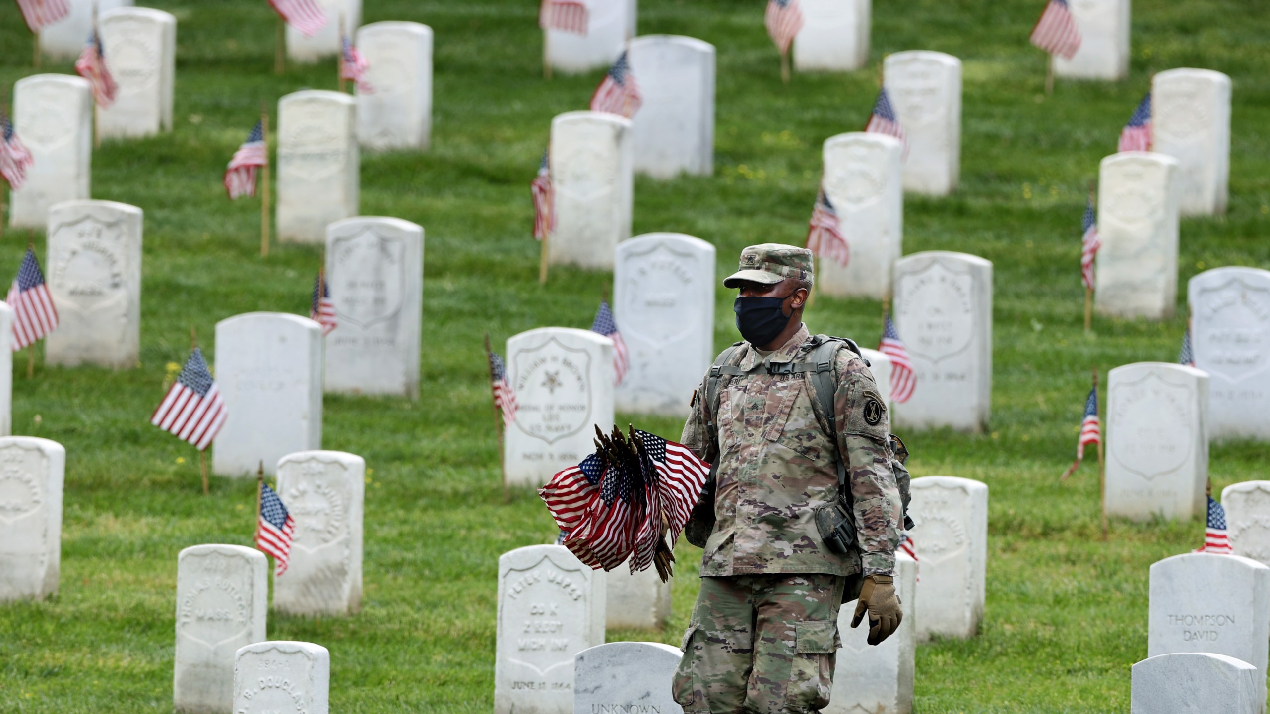 Wearing face masks to reduce the risk of spreading the novel coronavirus, a soldier from the 3rd Infantry Regiment, or the "Old Guard," works to place U.S. flags in front of every grave site ahead of the Memorial Day weekend in Arlington National Cemetery on May 21, 2020 in Arlington, Virginia. (Chip Somodevilla/Getty Images)