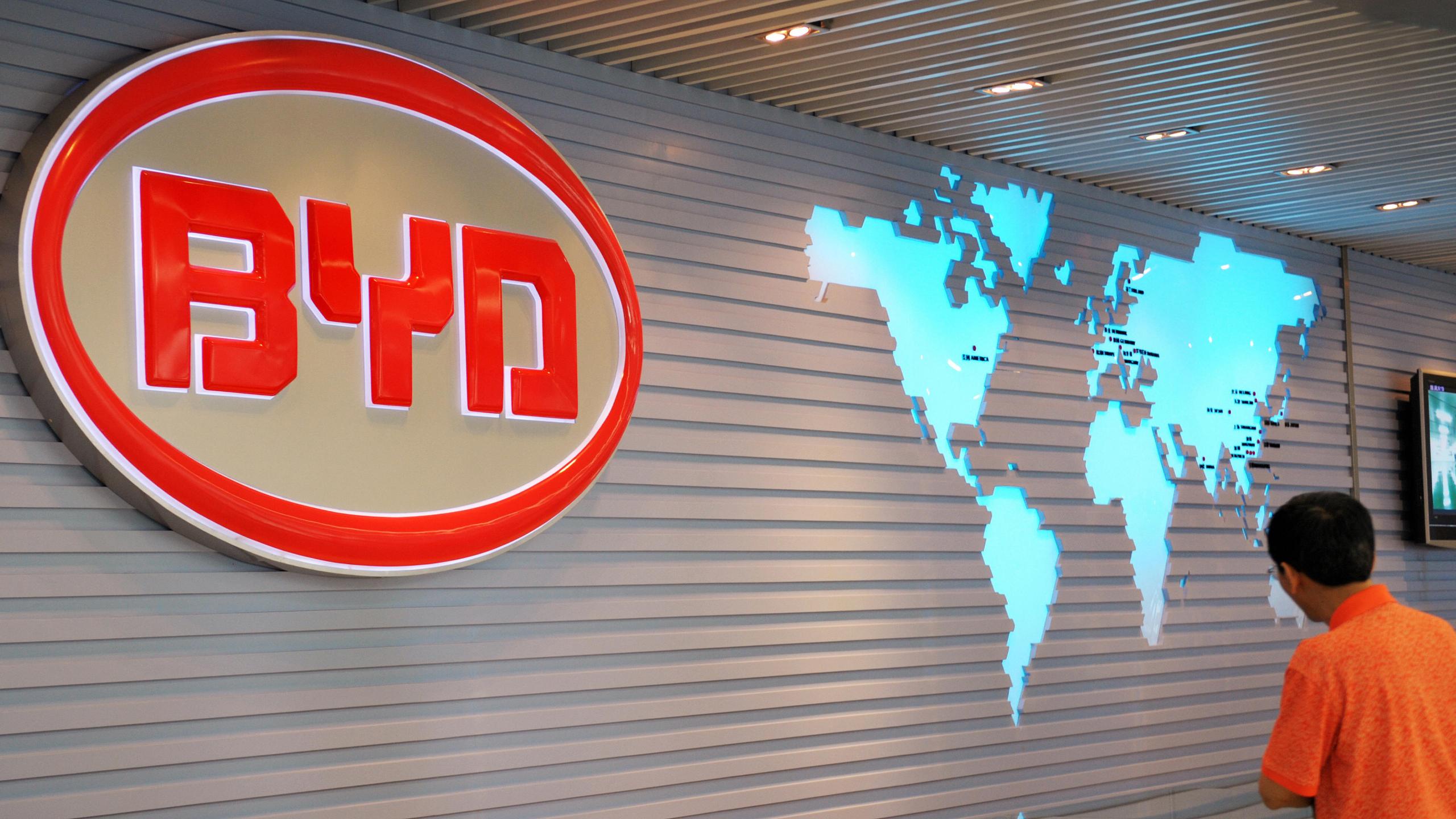 The BYD Auto (Build Your Dreams) logo looms over a scale model of the company's factory in Shenzhen on July 27, 2009. (LAURENT FIEVET/AFP via Getty Images)