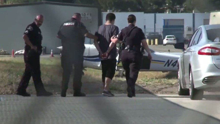 Police take an unlicensed pilot into custody following a rough landing in a stolen airplane at the Fullerton Municipal Airport on May 20, 2020. (Chip Yost)