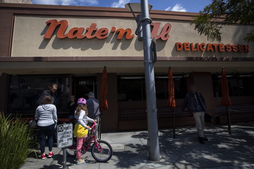 A small group of people gather to pick up food outside Nate ’n Al’s in March.(Francine Orr / Los Angeles Times)