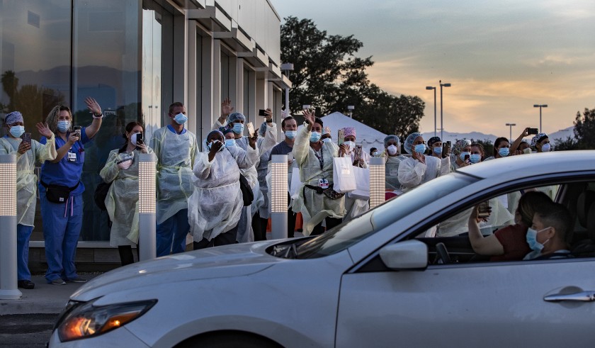 Doctors and nurses wave thanks as residents pay tribute to them during a drive-by rally honoring frontline heroes at Riverside University Health System in Moreno Valley.(Gina Ferazzi / Los Angeles Times)