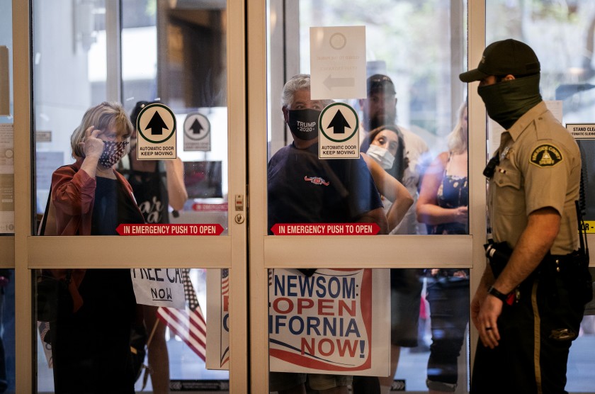 Residents who want public health orders rescinded wait to enter the County Administrative Center to speak during an emergency Riverside County Board of Supervisors meeting last week. (Gina Ferazzi / Los Angeles Times)