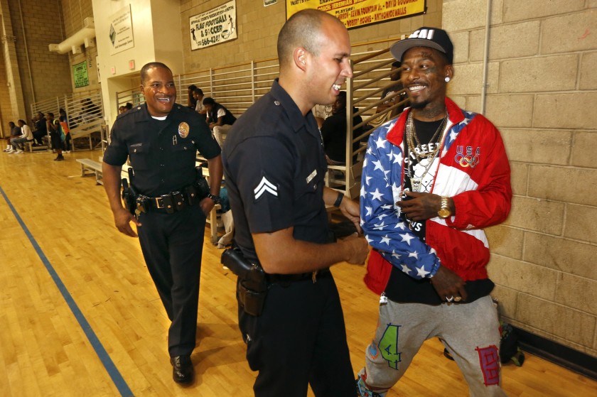 Eric Romero, right, a resident at the Imperial Courts Housing Development in Watts, chats with Los Angeles police officers Delano Hutchins, left, and Angelo Marzan in 2015. (Mel Melcon / Los Angeles Times)