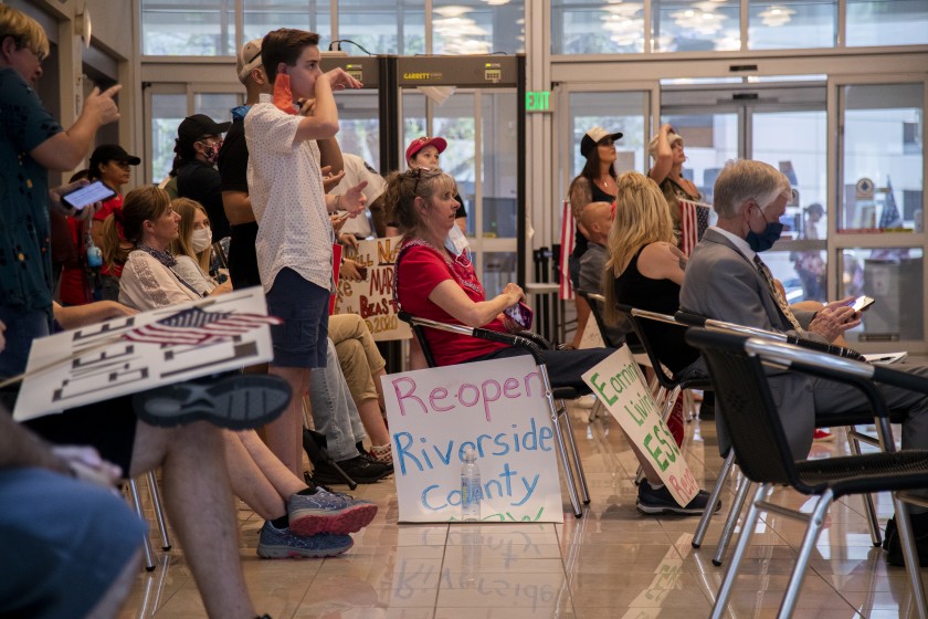 Residents who want public health orders rescinded crowd together in the lobby to watch video monitors of an emergency Riverside County Board of Supervisors meeting at the County Administrative Center on May 8, 2020. (Gina Ferazzi / Los Angeles Times)