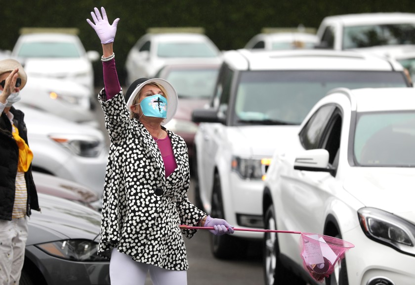 MaryAnn Lawson collects prayer requests from people gathering in their cars in a Santa Ana parking lot before an Easter service with the Rev. Robert A. Schuller on April 12, 2020. (Christina House / Los Angeles Times)