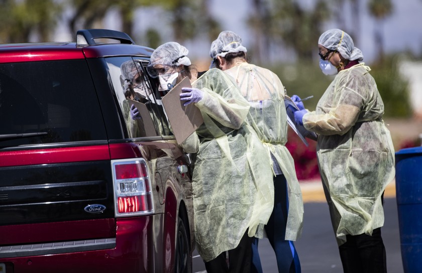 Riverside County medical personnel screen a carload of people at a coronavirus drive-though testing facility on March 24, 2020. (Gina Ferazzi / Los Angeles Times)