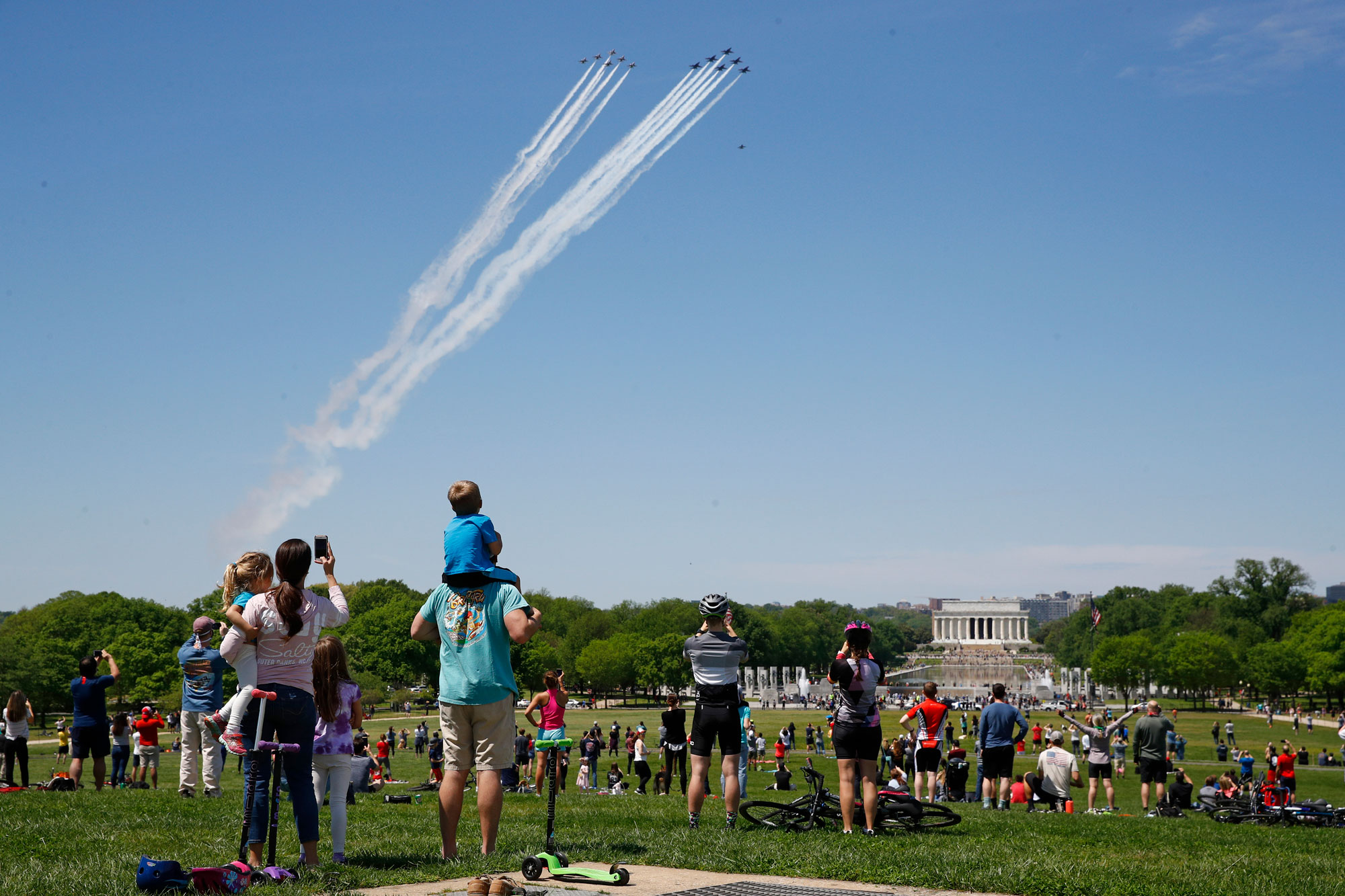 People view the U.S. Navy Blue Angels and U.S. Air Force Thunderbirds as they fly over the National Mall in Washington, Saturday, May 2, 2020. The flyover was in salute to first responders in the fight against the coronavirus pandemic. (AP Photo/Patrick Semansky via CNN)