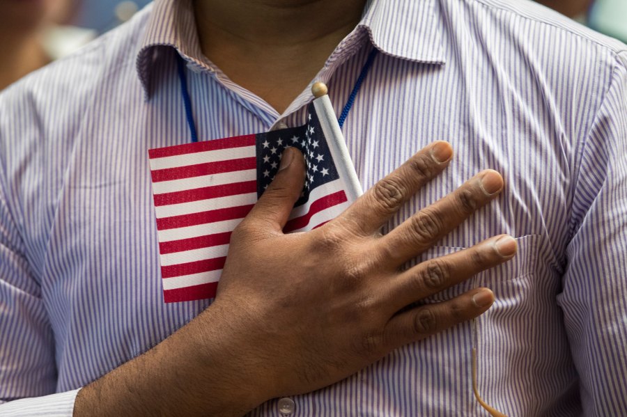 A new U.S. citizen holds a flag to his chest during the Pledge of Allegiance during a naturalization ceremony at the New York Public Library, July 3, 2018 in New York City. (Drew Angerer/Getty Images)