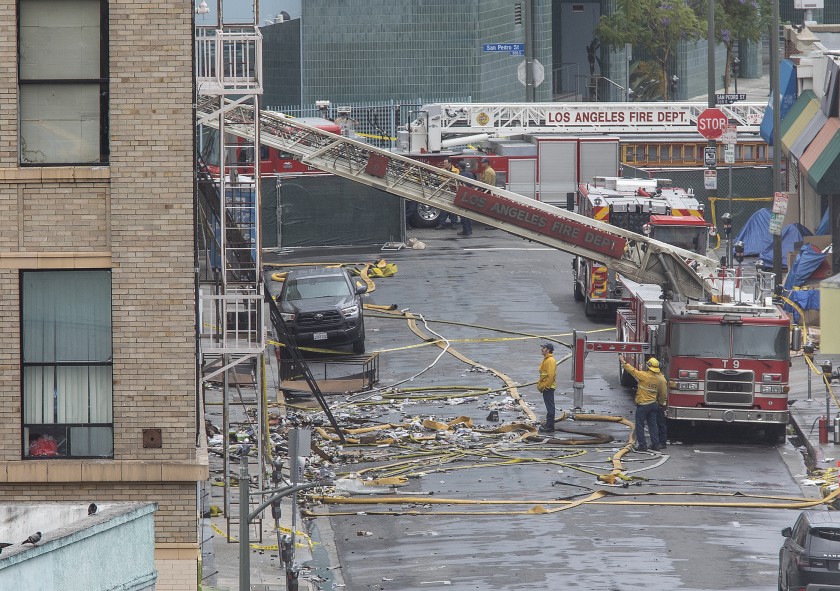 Members of the Los Angeles Fire Department investigate the scene of a fiery explosion on Boyd Street in the downtown Los Angeles that injured 12 firefighters and damaged buildings and fire equipment.(Gary Coronado / Los Angeles Times)