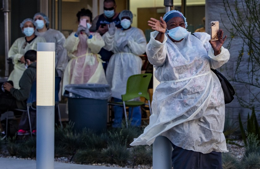 Traveling nurse Gail Cunningham waves thanks as residents pay tribute to her and her medical personnel during a drive-by rally honoring frontline heroes in the midst of the coronavirus pandemic at the emergency room entrance to Riverside University Health System in Moreno Valley in this 2020 photo. (Gina Ferazzi/Los Angeles Times)