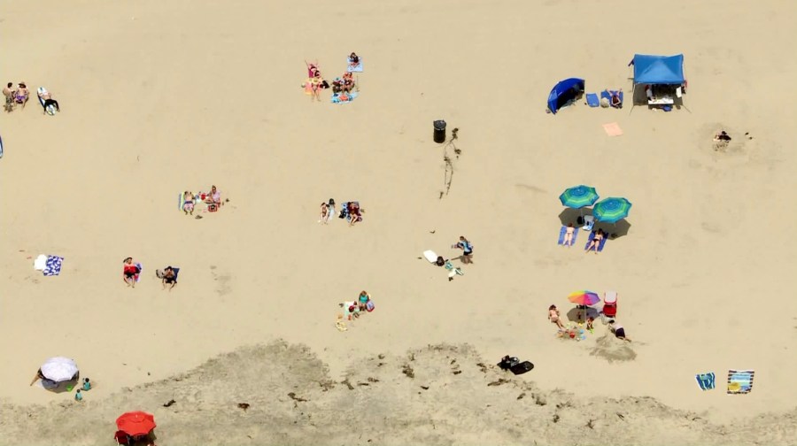 People lounge on the sand in Huntington Beach despite ongoing coronavirus orders mandating beachgoers stay active on May 7, 2020. (Credit: KTLA)