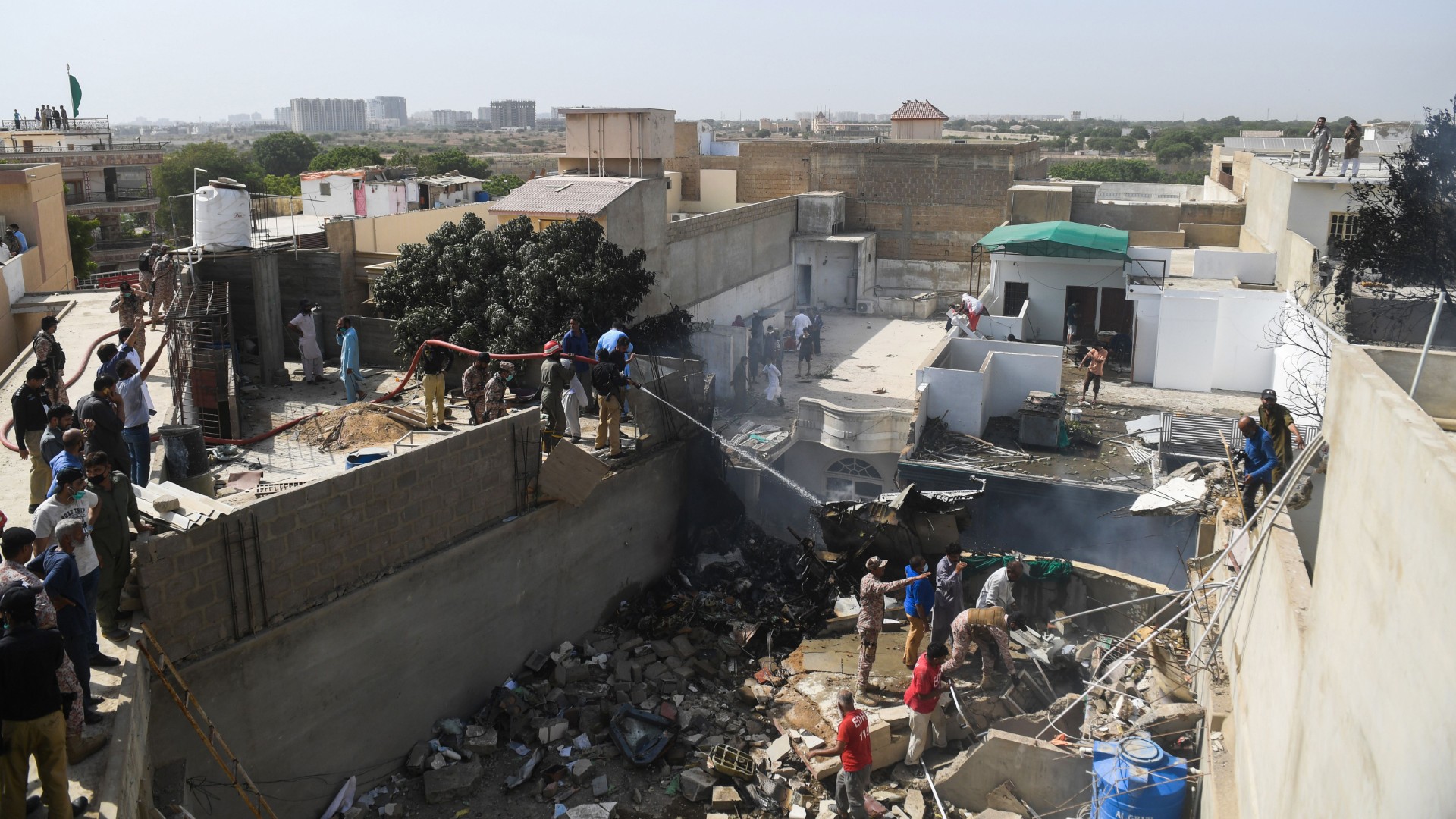 Rescue workers spray water on the part of a Pakistan International Airlines aircraft after it crashed at a residential area in Karachi on May 22, 2020. (ASIF HASSAN/AFP via Getty Images)