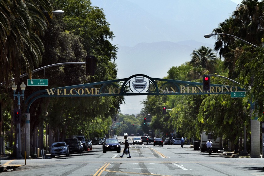 A pedestrian walks under a sign for the city of San Bernardino in this undated photo. (Irfan Khan / Los Angeles Times)