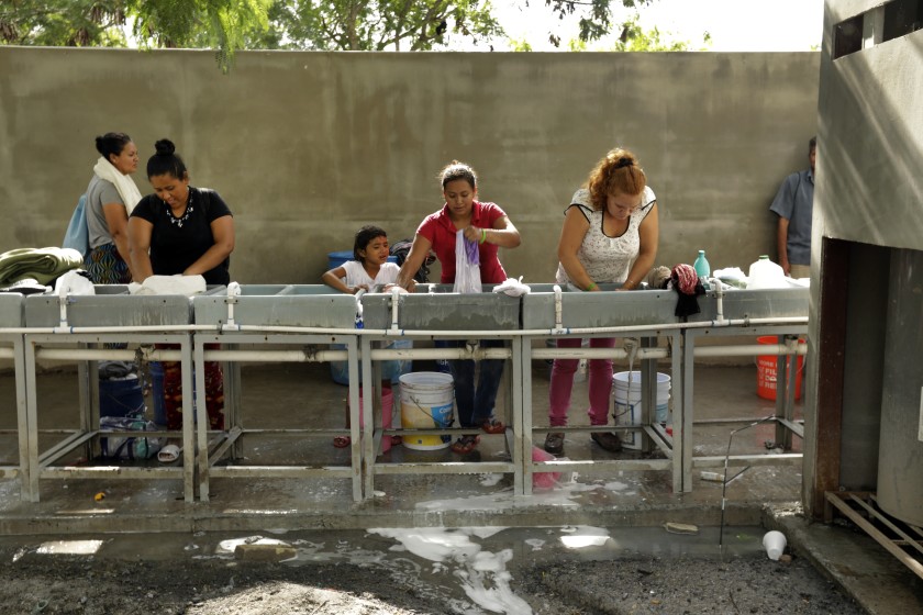 Migrants are seen in an undated photo washing their clothes at the Matamoros refugee camp, where hundreds of asylum seekers are waiting for U.S. court hearings under the “Remain in Mexico” program. (Carolyn Cole / Los Angeles Times)