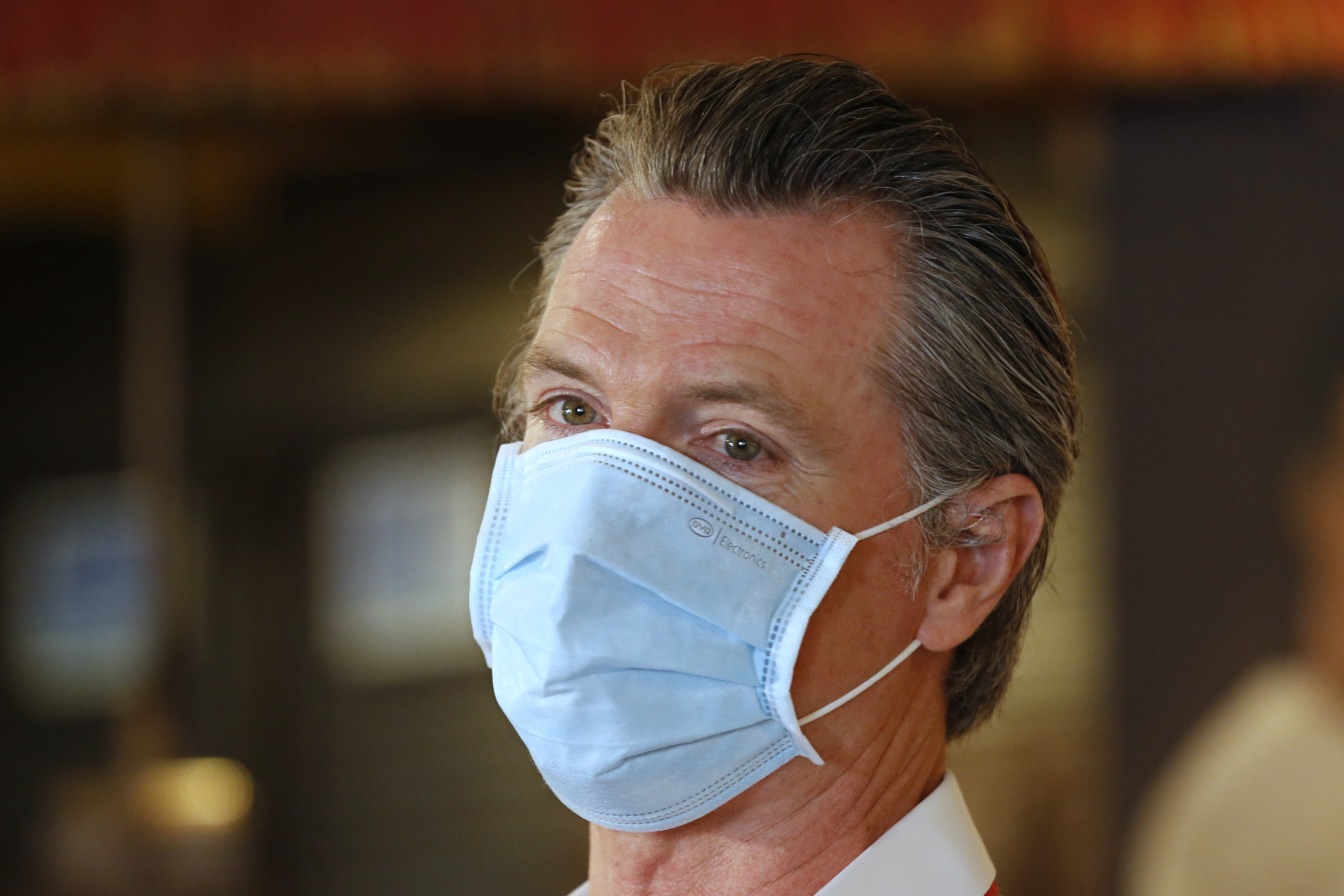 In this June 19, 2020, file photo, California Gov. Gavin Newsom, wears a face mask as he answers a reporter's question during his visit to the Queen Sheba Ethiopian Cuisine restaurant in Sacramento, Calif. Newsom implored people Monday, June 22, 2020, to wear face coverings to protect against the coronavirus and allow businesses to safely open after several days in which the state saw its highest virus hospitalizations and number of infections to date. (AP Photo/Rich Pedroncelli, Pool)