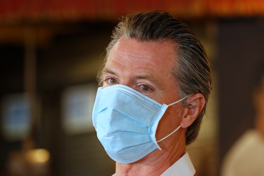 In this June 19, 2020, file photo, California Gov. Gavin Newsom, wears a face mask as he answers a reporter's question during his visit to the Queen Sheba Ethiopian Cuisine restaurant in Sacramento, Calif. Newsom implored people Monday, June 22, 2020, to wear face coverings to protect against the coronavirus and allow businesses to safely open after several days in which the state saw its highest virus hospitalizations and number of infections to date. (AP Photo/Rich Pedroncelli, Pool)