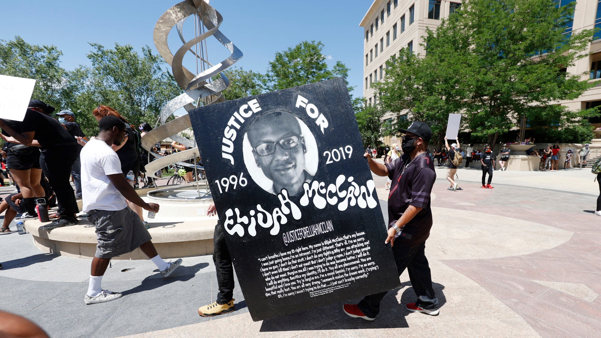 In this June 27, 2020, file photo, demonstrators carry a giant placard during a rally and march over the death of 23-year-old Elijah McClain outside the police department in Aurora, Colorado. (David Zalubowski/Associated Press)