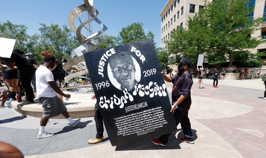 In this June 27, 2020, file photo, demonstrators carry a giant placard during a rally and march over the death of 23-year-old Elijah McClain outside the police department in Aurora, Colorado. (David Zalubowski/Associated Press)