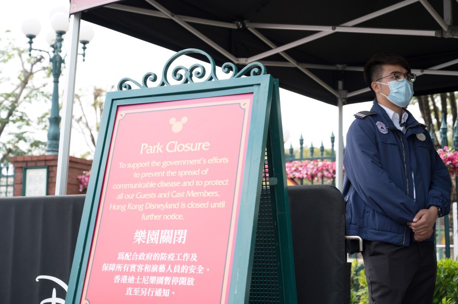 A member of staff wearing a mask stands next to a sign announcing the park's closure at Hong Kong Disneyland in Hong Kong on January 26, 2020, after it announced it was shutting its doors until further notice over a deadly virus outbreak in central China. (Ayaka MCGILL / AFP/Getty Images)