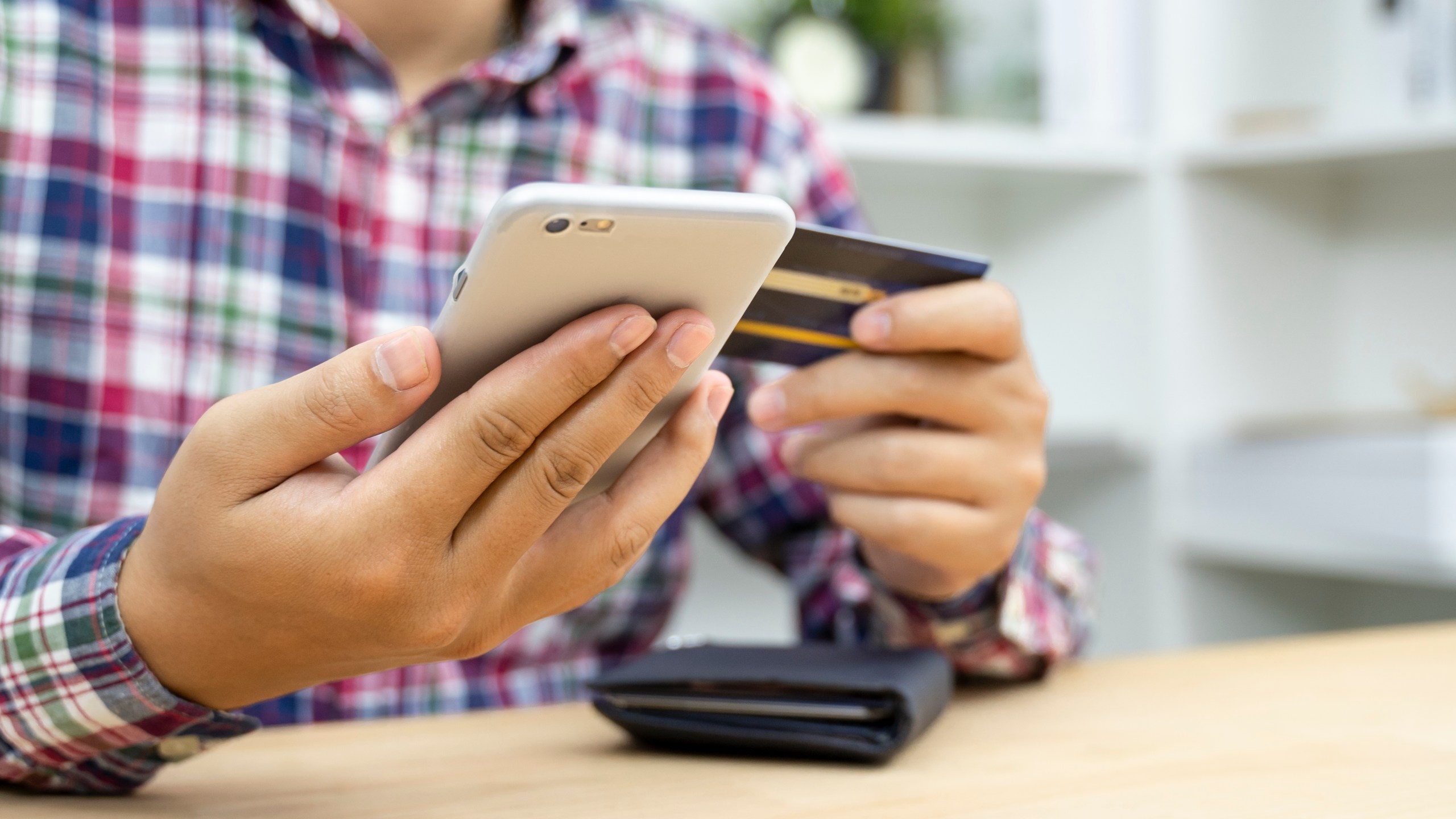 This file photo shows a man holding a credit card and using a phone. (Getty Images)