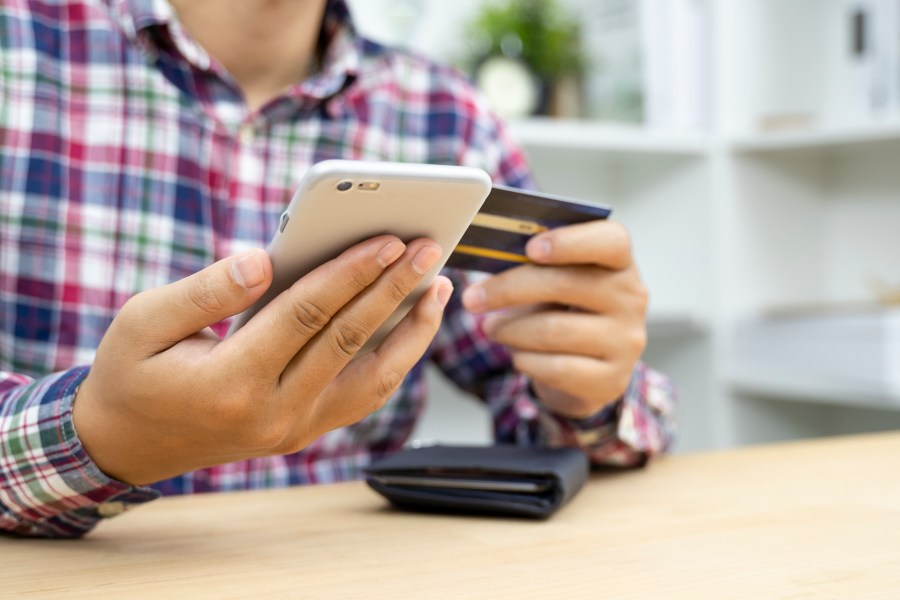 This file photo shows a man holding a credit card and using a phone. (Getty Images)