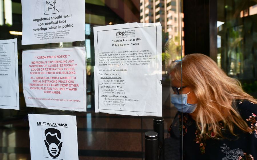 A woman wearing a face mask enters a building where the Employment Development Department has its offices in Los Angeles on May 4, 2020. (FREDERIC J. BROWN/AFP via Getty Images)