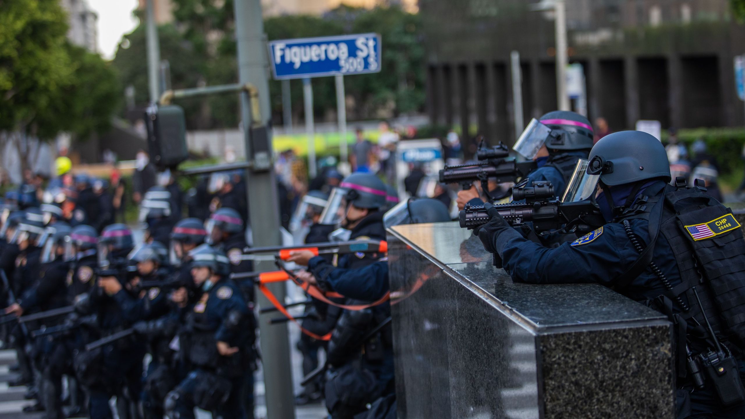 Police stand in a skirmish line while demonstrators after they throw stones in their direction in downtown Los Angeles on May 30, 2020. During another incident in the area that day, an officer fired at a man who police say was driving towards officers. (APU GOMES/AFP via Getty Images)