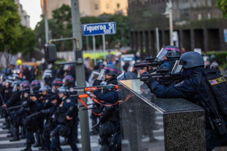 Police stand in a skirmish line while demonstrators after they throw stones in their direction in downtown Los Angeles on May 30, 2020. During another incident in the area that day, an officer fired at a man who police say was driving towards officers. (APU GOMES/AFP via Getty Images)