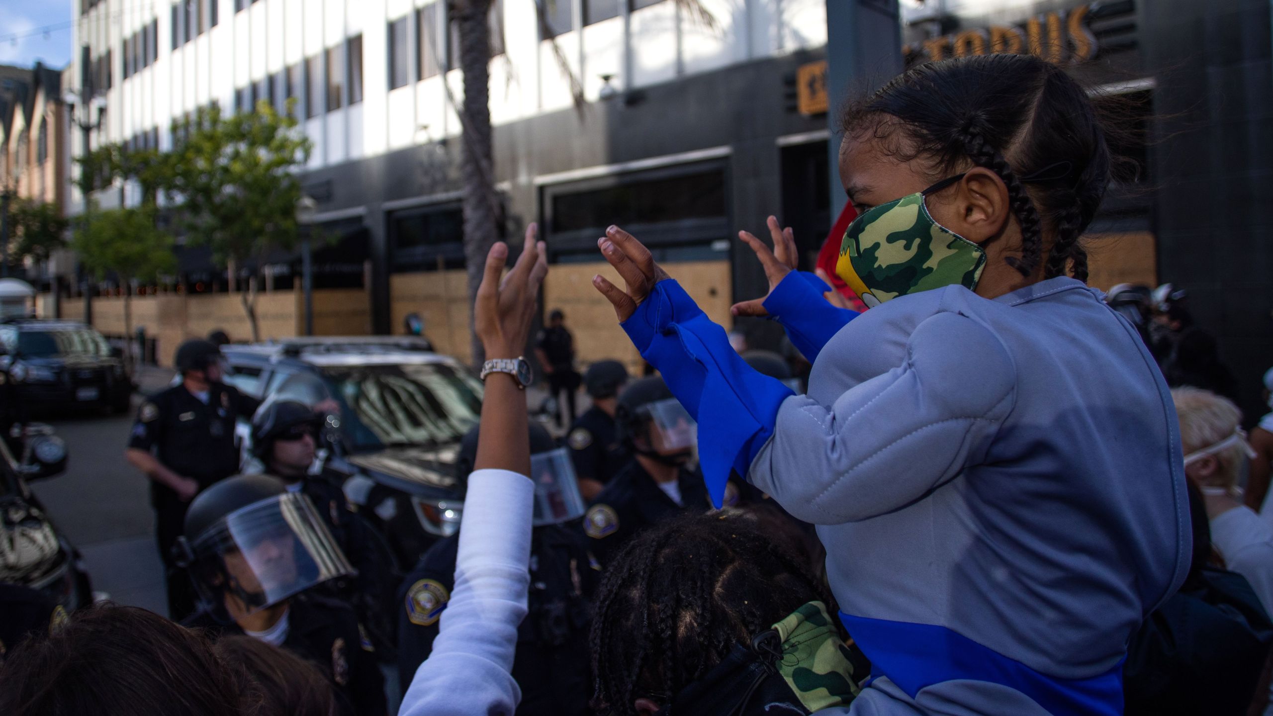 A child holds up his hands in front of a row of police officers in downtown Long Beach on May 31, 2020 during a protest against the death of George Floyd. (APU GOMES/AFP via Getty Images)