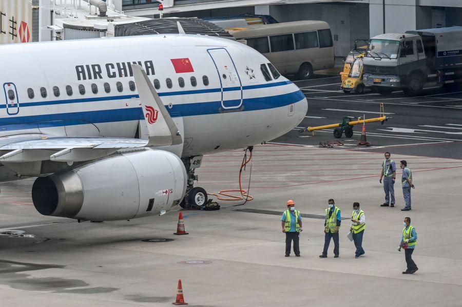 Employees work next to an Air China plane following preventive procedures against the spread of the COVID-19 coronavirus in Pudong International Airport in Shanghai on June 11, 2020. (HECTOR RETAMAL/AFP via Getty Images)