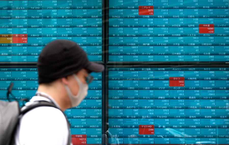 A pedestrian walks in front of an electronic quotation board displaying stock prices of the Tokyo Stock Exchange in Tokyo on June 12, 2020. (KAZUHIRO NOGI/AFP via Getty Images)