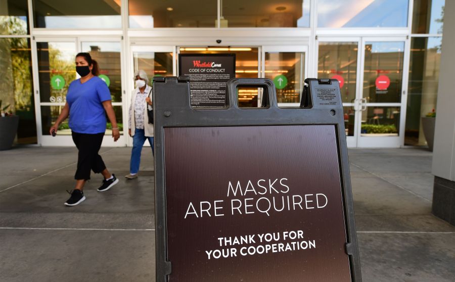 Women wearing face masks exit a shopping mall where a sign is posted at an entrance reminding people of the mask requirement at Westfield Santa Anita mall in Arcadia on June 12, 2020. (FREDERIC J. BROWN/AFP via Getty Images)