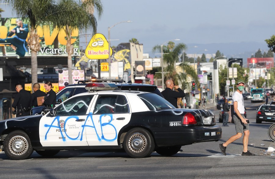 A man walks past a defaced LAPD vehicle in the Fairfax District, an area damaged during civil unrest, following demonstrations in response to George Floyd’s death on May 31, 2020, in Los Angeles. (Mario Tama/Getty Images)