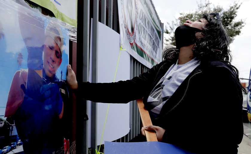 Jennifer Guardado touches a picture of her brother, Andres Guardado, as she grieves on June 20, 2020, at the location near Gardena where the 18-year-old Latino youth was shot and killed by L.A. County Sheriff’s deputies. (Luis Sinco / Los Angeles Times)