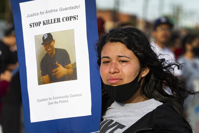 A photo of 18-year-old Andres Guardado is held by his 22-year-old sister, Jennifer, during a rally in Gardena in June 2020. (Damian Dovarganes / Associated Press)