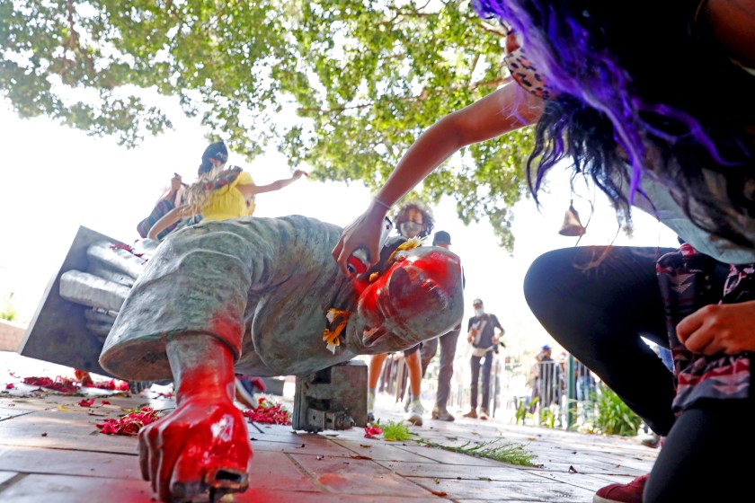 Activists topple and deface with red paint the statue of Father Junipero Serra at Father Serra Park in El Pueblo de Los Ángeles in downtown Los Angeles on June 20, 2020. (Gary Coronado/Los Angeles Times)