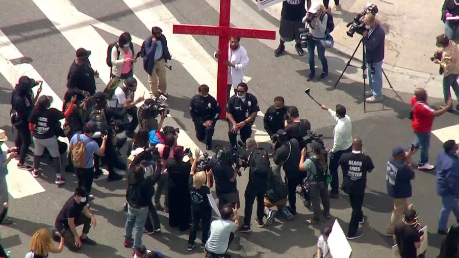 LAPD officers kneel in front of a cross in downtown Los Angeles on June 2, 2020. (KTLA)