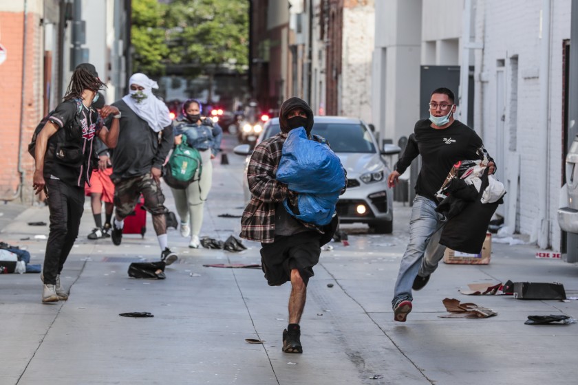 Looters rush away from police after picking through a store in downtown Santa Monica on May 31, 2020. (Robert Gauthier/Los Angeles Times)