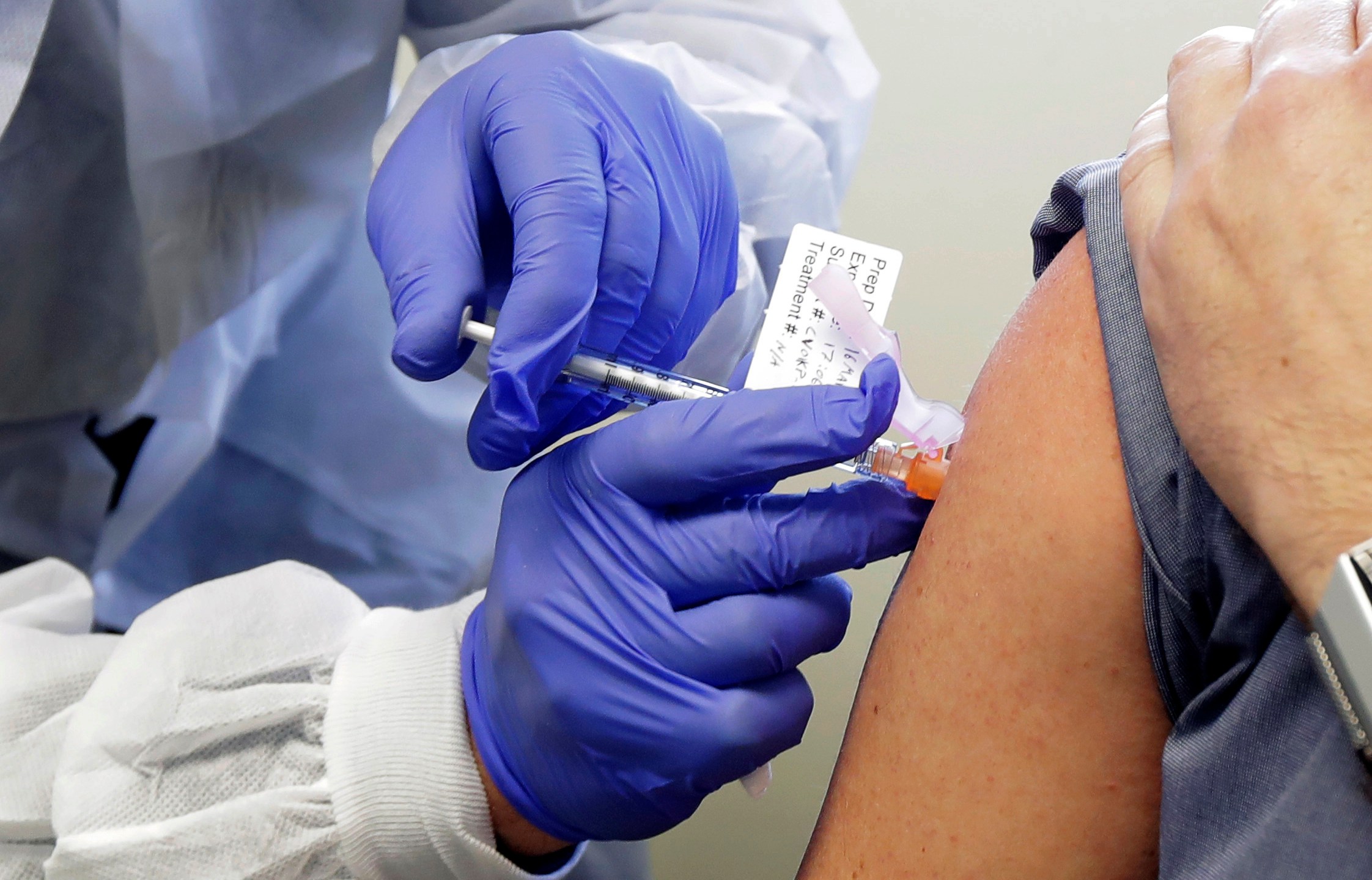 Neal Browning receives a shot in the first-stage safety study clinical trial of a potential vaccine for COVID-19, the disease caused by the new coronavirus, Monday, March 16, 2020, at the Kaiser Permanente Washington Health Research Institute in Seattle. Browning is the second patient to receive the shot in the study. (AP Photo/Ted S. Warren)