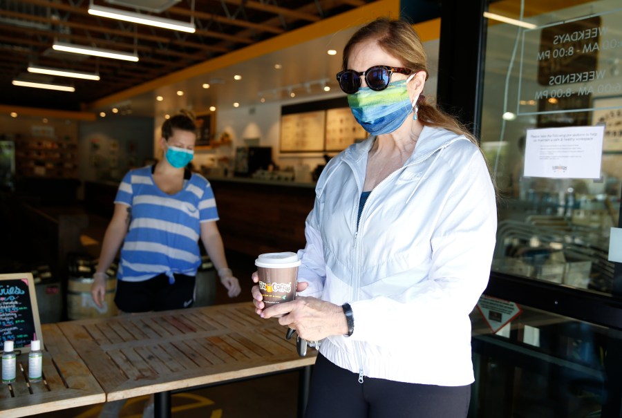 Barbara Meier, right, wears a face mask as picks up her drink order from Philz Coffee in Davis on April 27, 2020. (Rich Pedroncelli/Associated Press)