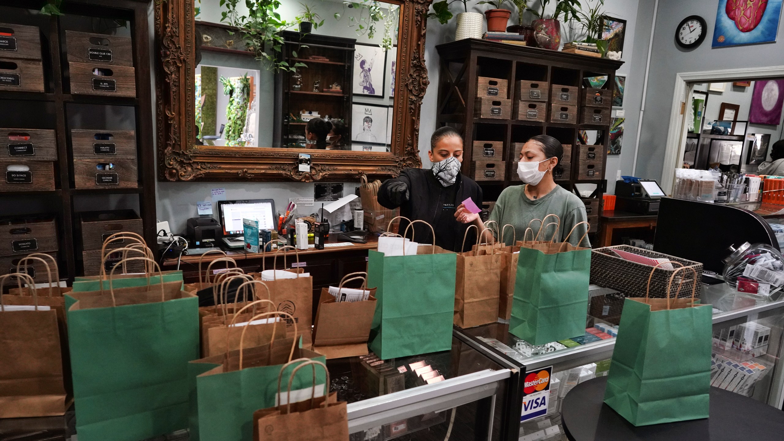 In this April 16, 2020, file photo, budtenders wearing protective masks prepare orders for customers to pick up at the Higher Path cannabis dispensary in the Sherman Oaks. (AP Photo/Richard Vogel, File)