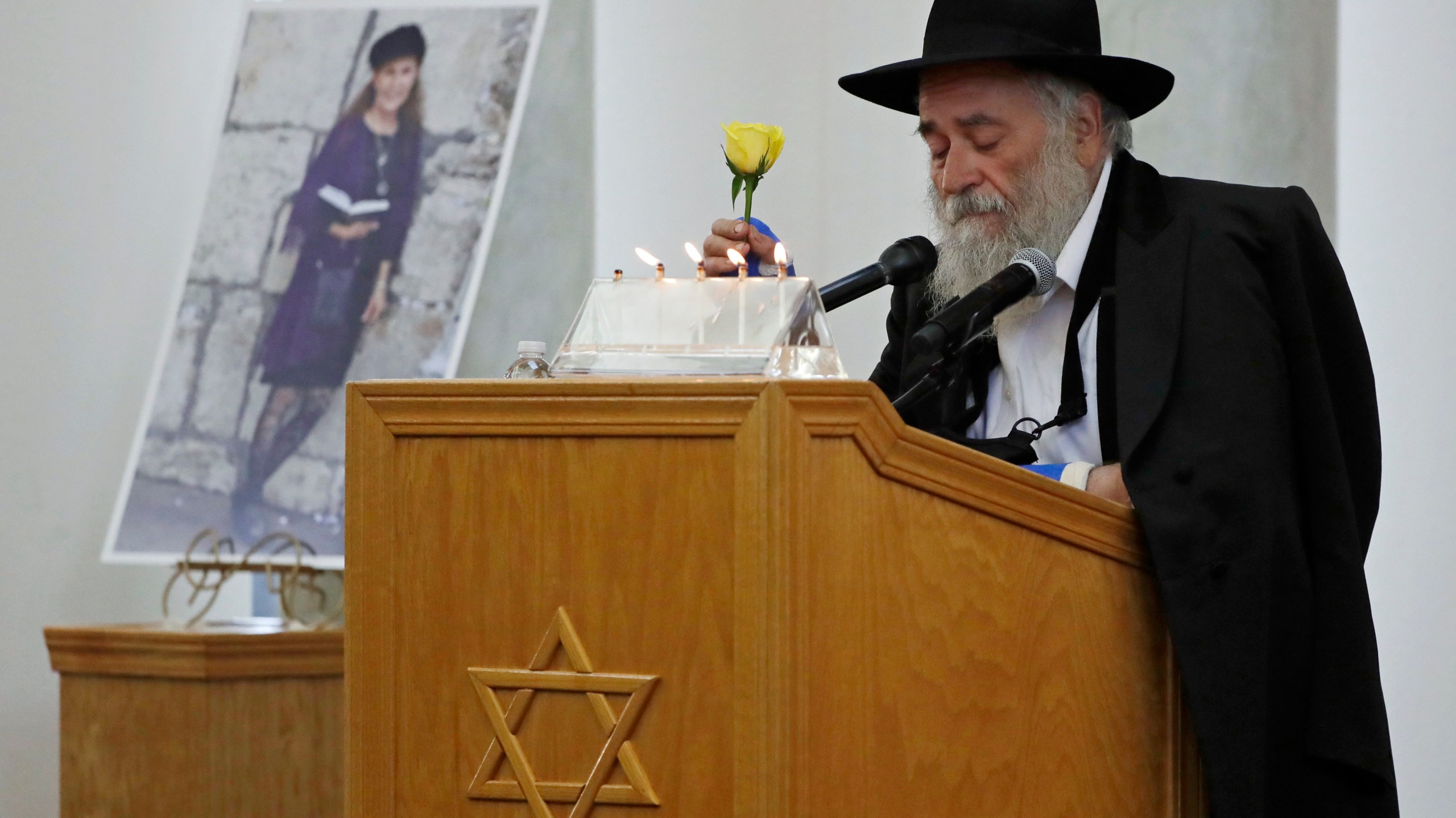 Yisroel Goldstein, Rabbi of Chabad of Poway, holds a yellow rose as he speaks at the funeral for Lori Gilbert-Kaye, who is pictured at left, in Poway on April 29, 2019. (AP Photo/Gregory Bull, File)