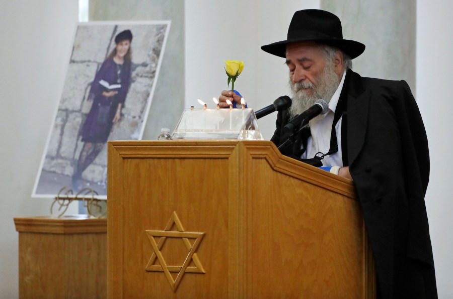 Yisroel Goldstein, Rabbi of Chabad of Poway, holds a yellow rose as he speaks at the funeral for Lori Gilbert-Kaye, who is pictured at left, in Poway on April 29, 2019. (AP Photo/Gregory Bull, File)