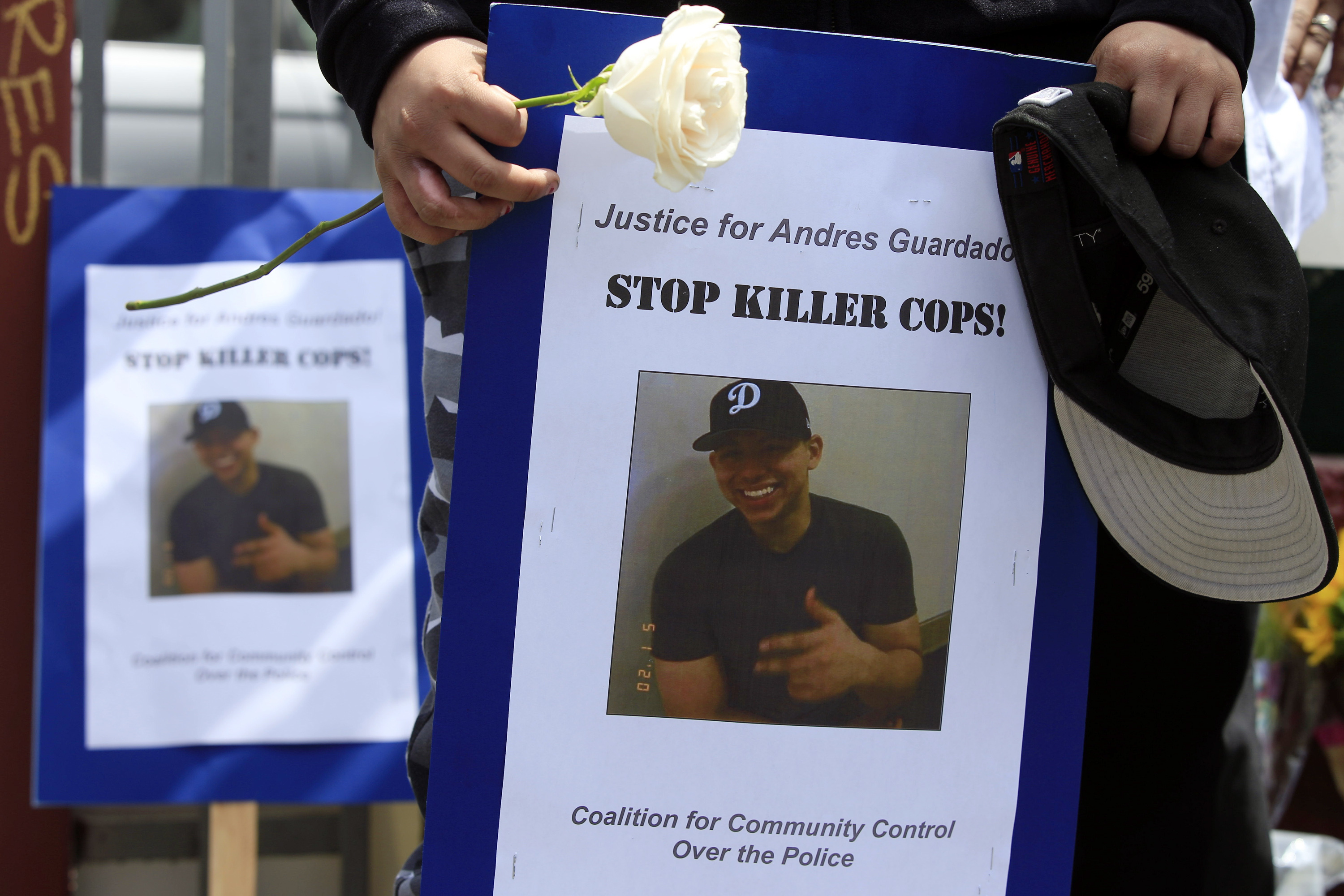 Mourners hold images of Andres Guardado at a memorial site in Gardena on June 19, 2020. (AP Photo/Damian Dovarganes)