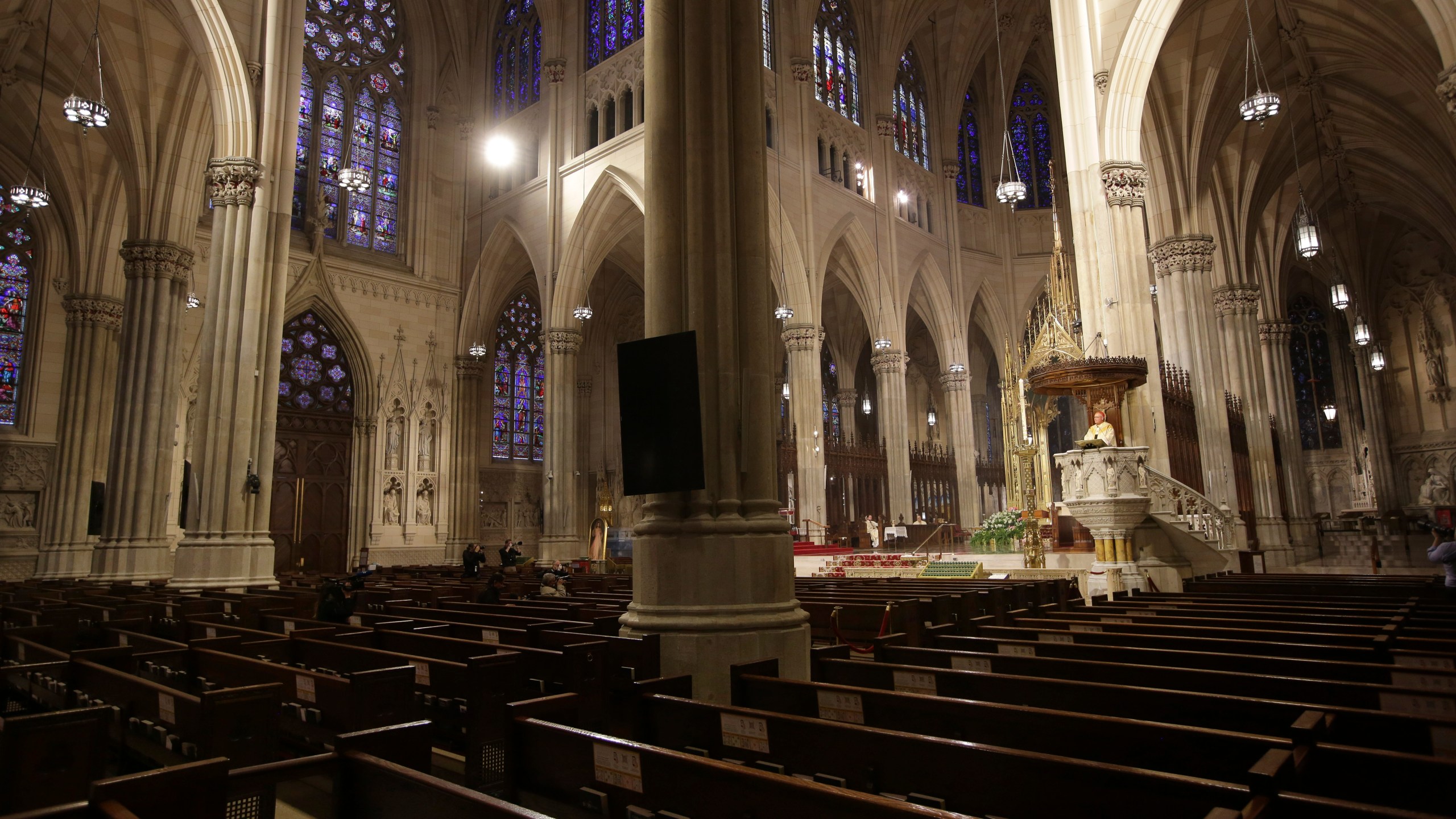 Archbishop Timothy Dolan, right, delivers his homily over mostly empty pews as he leads an Easter Mass at St. Patrick's Cathedral in New York on April 12, 2020. (AP Photo/Seth Wenig)